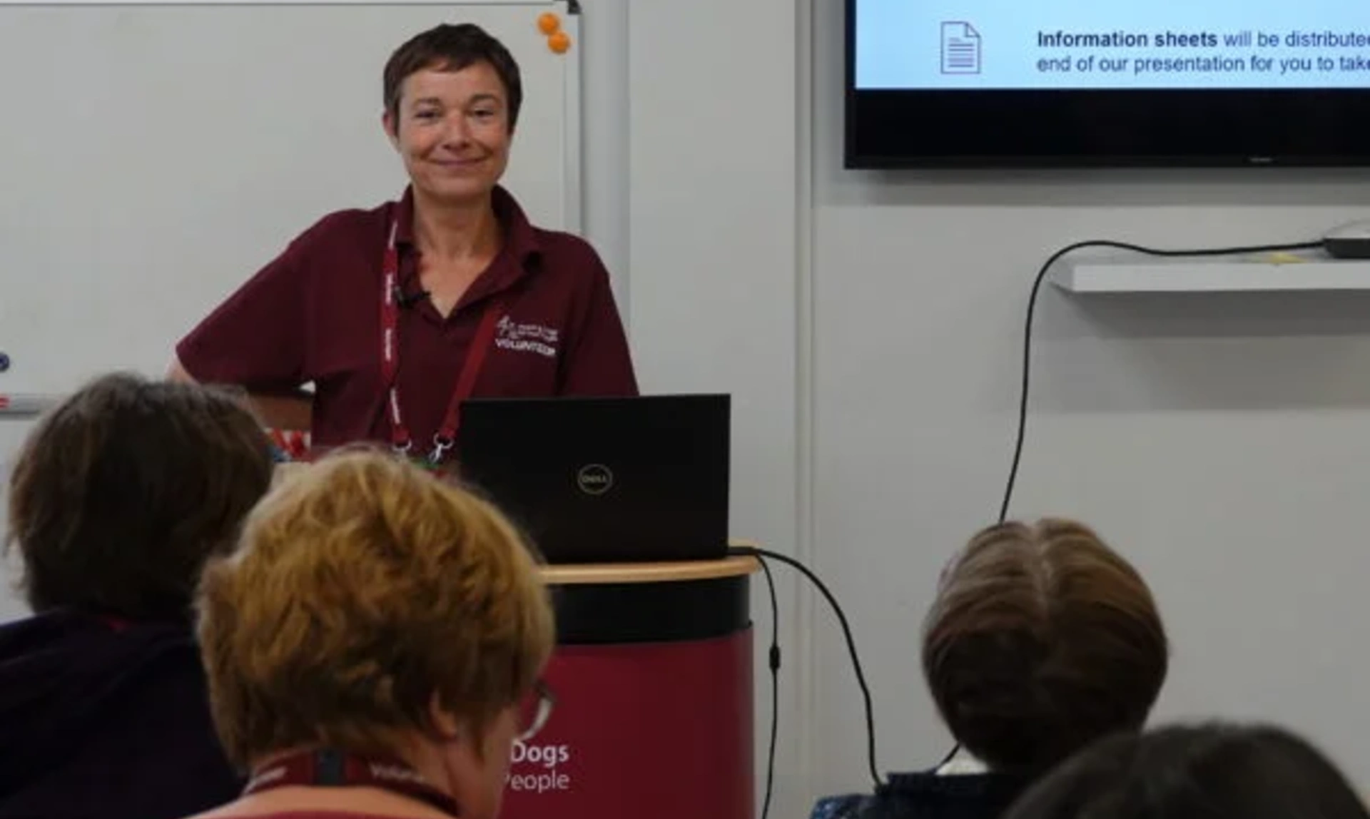 Smiling Peer Support volunteer standing in front of an audience