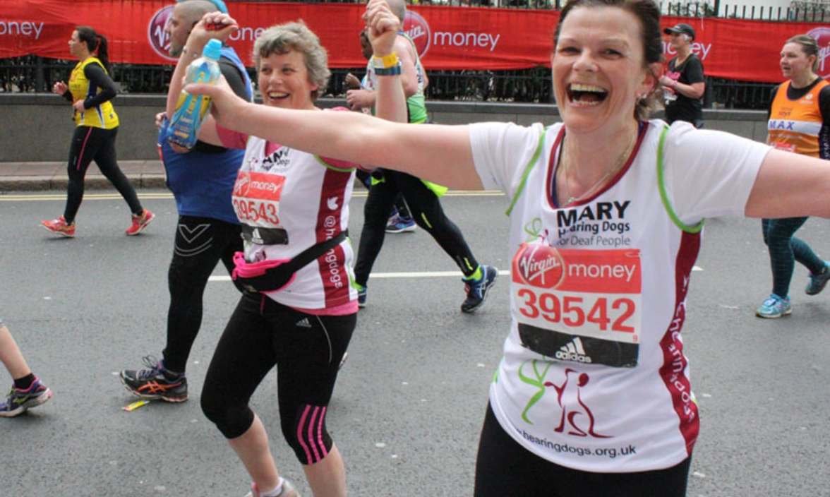 Two smiling Hearing Dogs runners in branded running tops