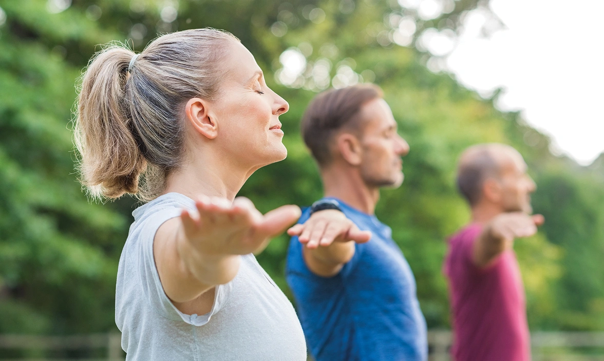 Midshot side view of three people with their eyes closed and arms out at their sides