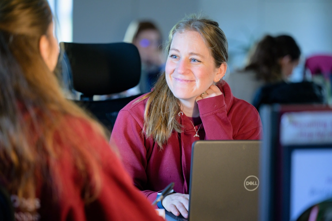 A woman sat at a desk smiling at another woman facing her