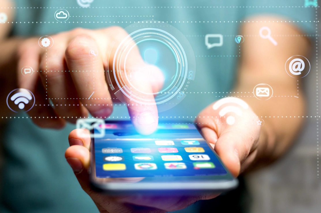 Close up on a hand holding a mobile phone with icons floating in the air around it