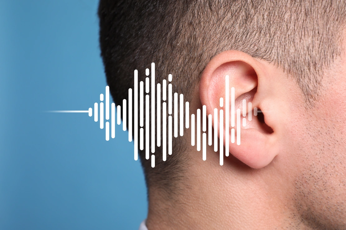 Close up, side view of a person’s ear with white broken soundwaves going into the ear
