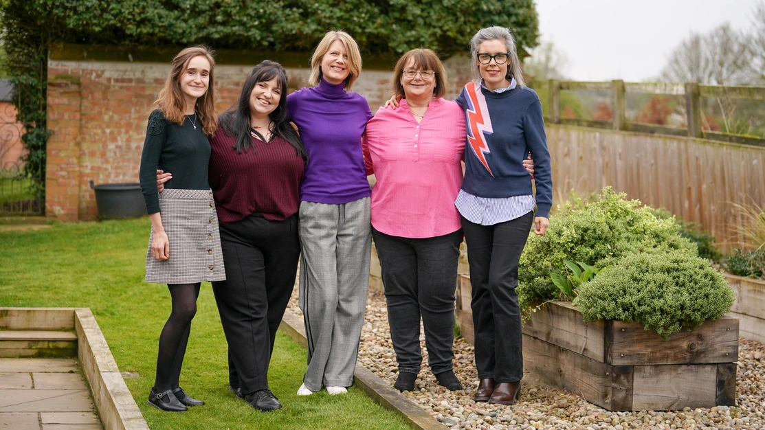 A group of five women standing outside smiling