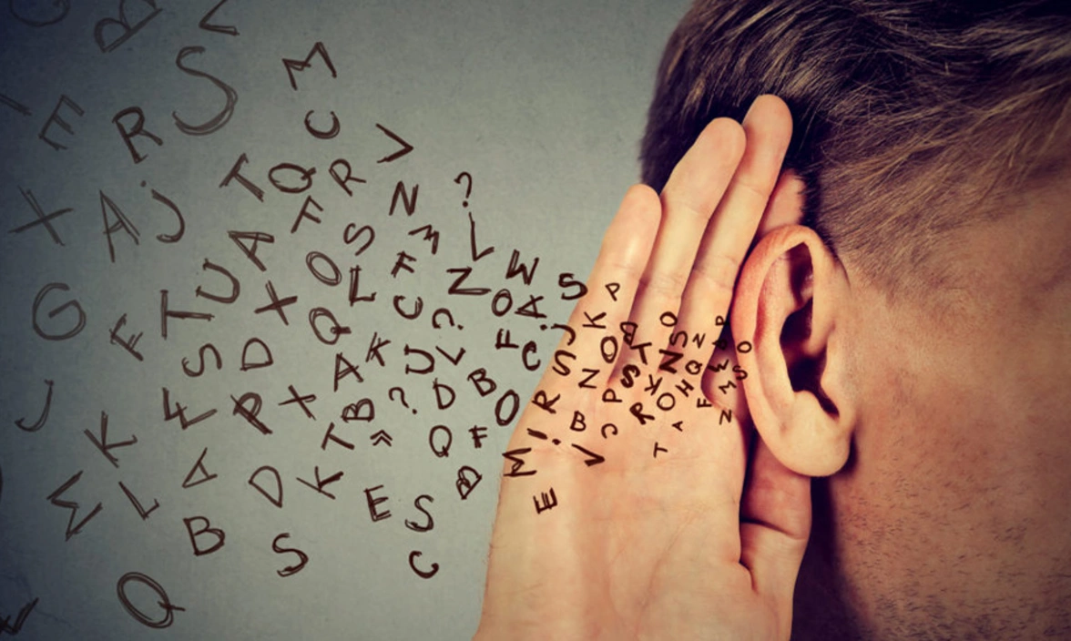 A person with his hand to his ear and a jumble of letters flowing into his ear