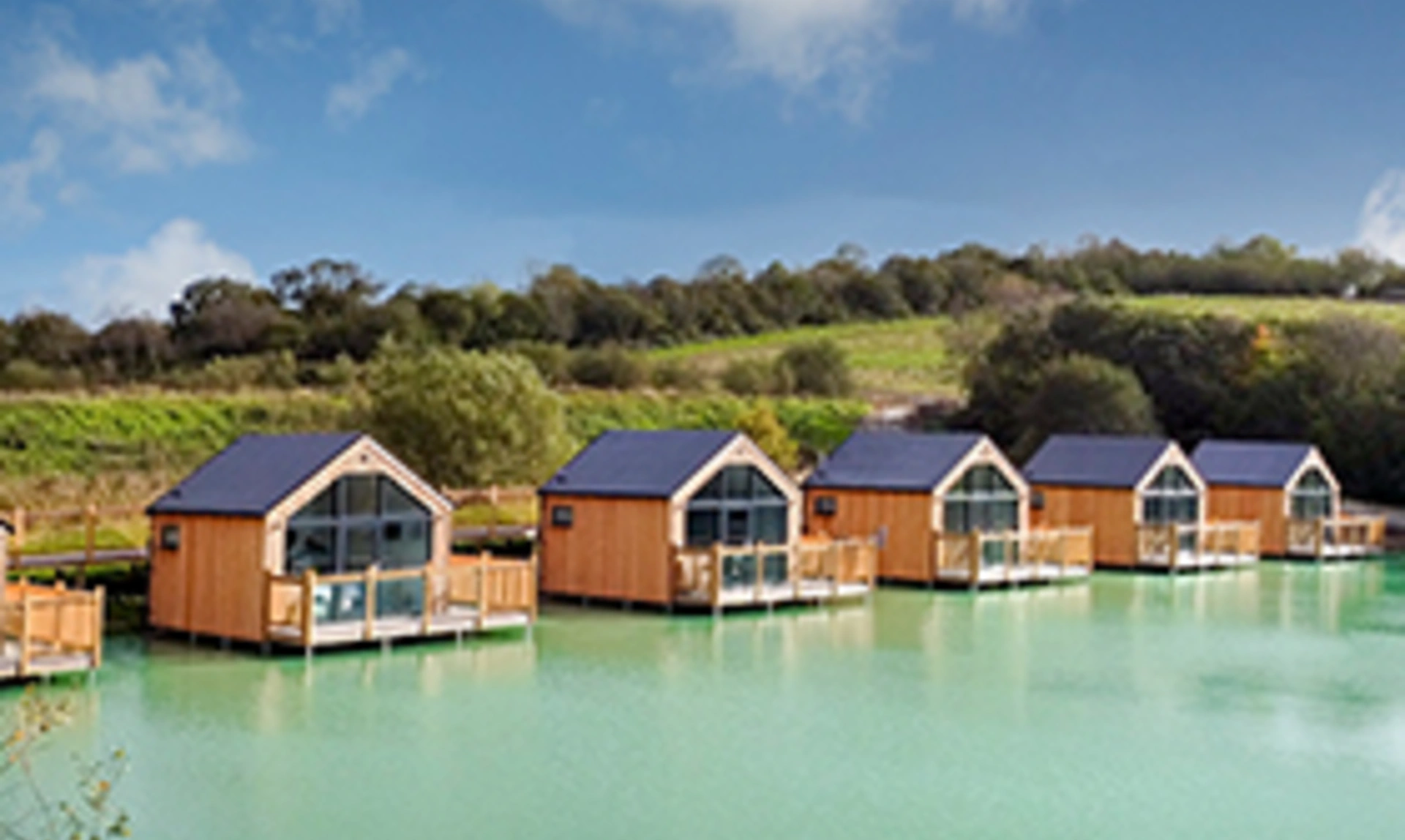 Lodges on a lake with blue sky and fields in the background