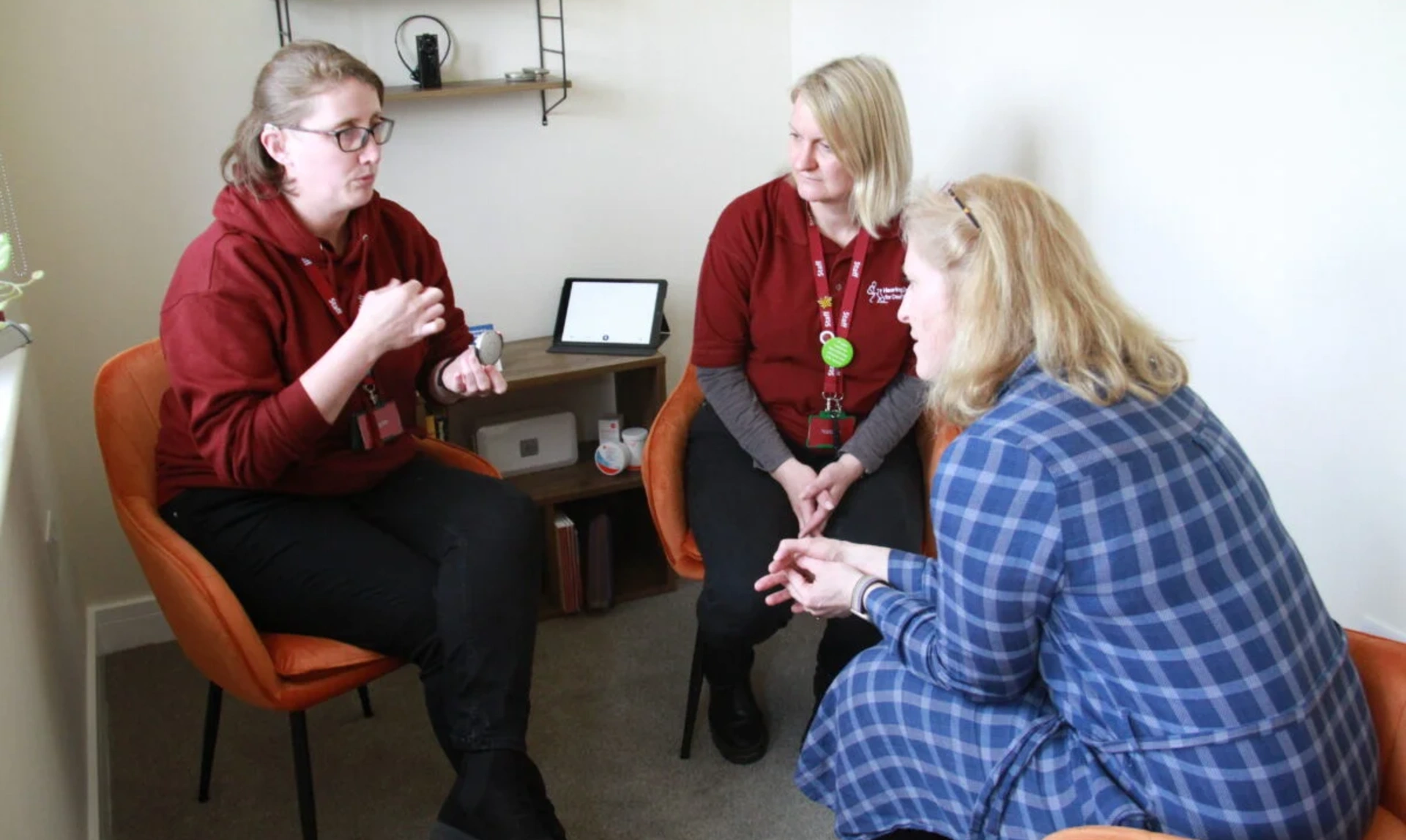 A group of women, one of whom is demonstrating a piece of hearting loss technology
