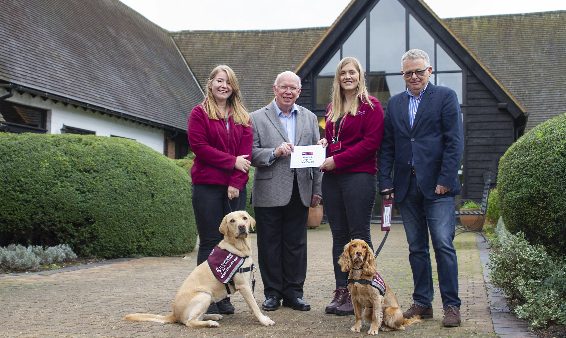 Group of people and a labrador and spaniel standing outside the Grange