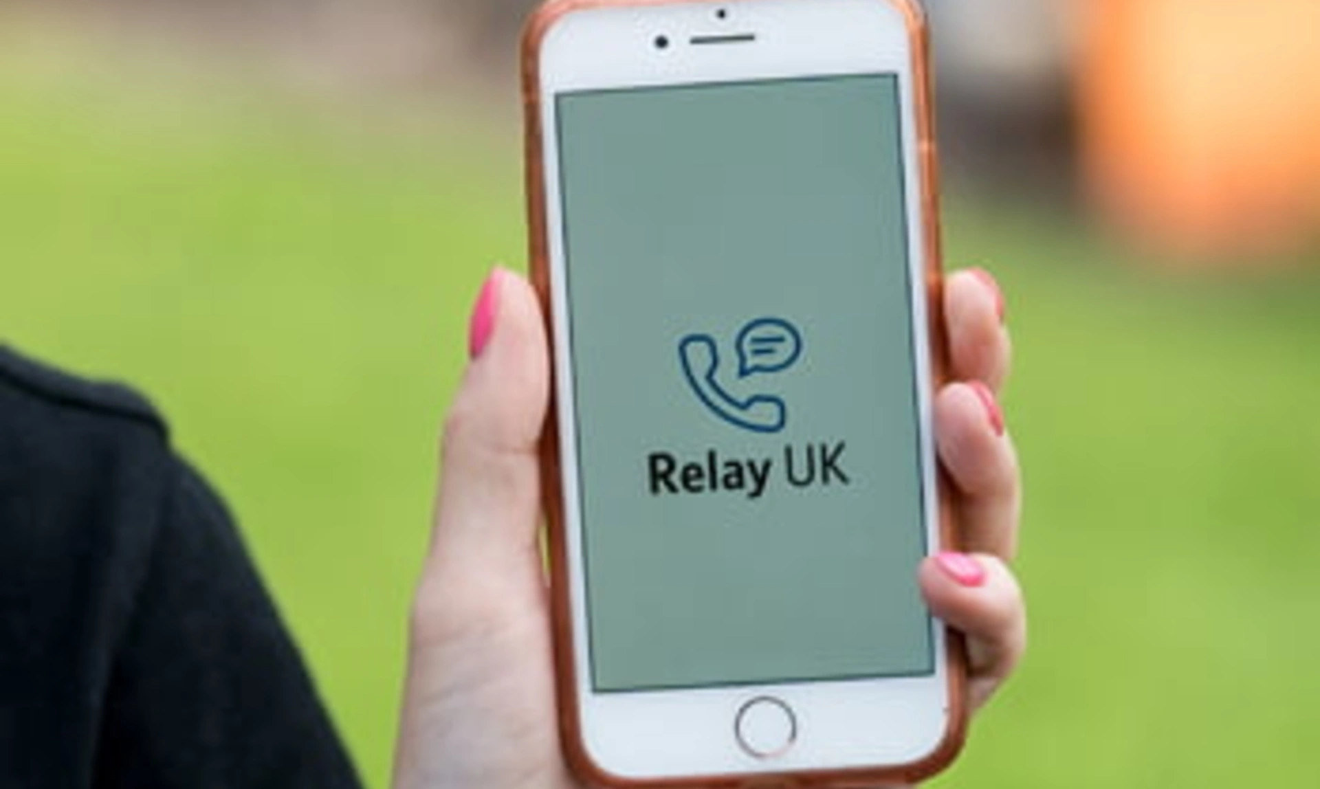 Close up of a hand holding a mobile phone, the screen says ‘Relay UK’