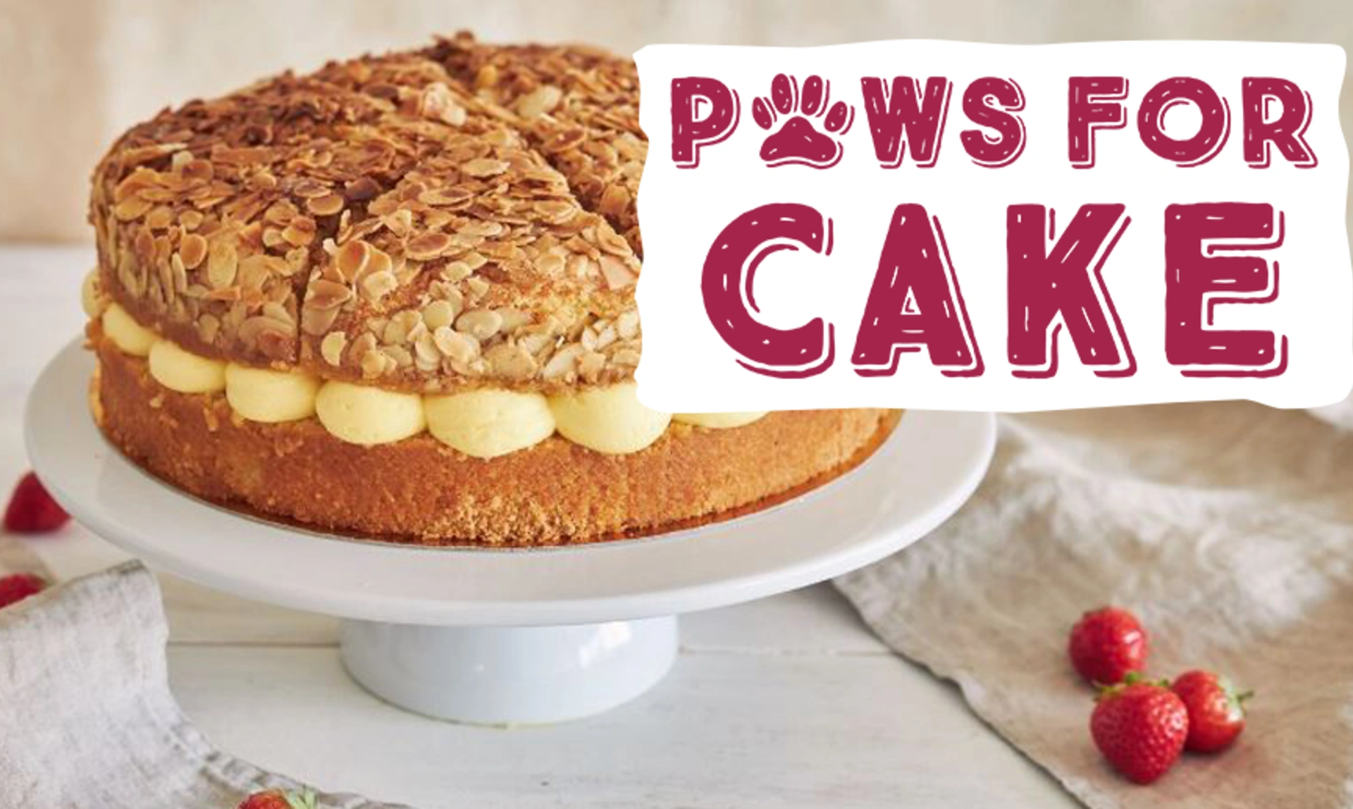 A brown cake with buttercream icing on a fancy cake stand and the Paws for Cake logo