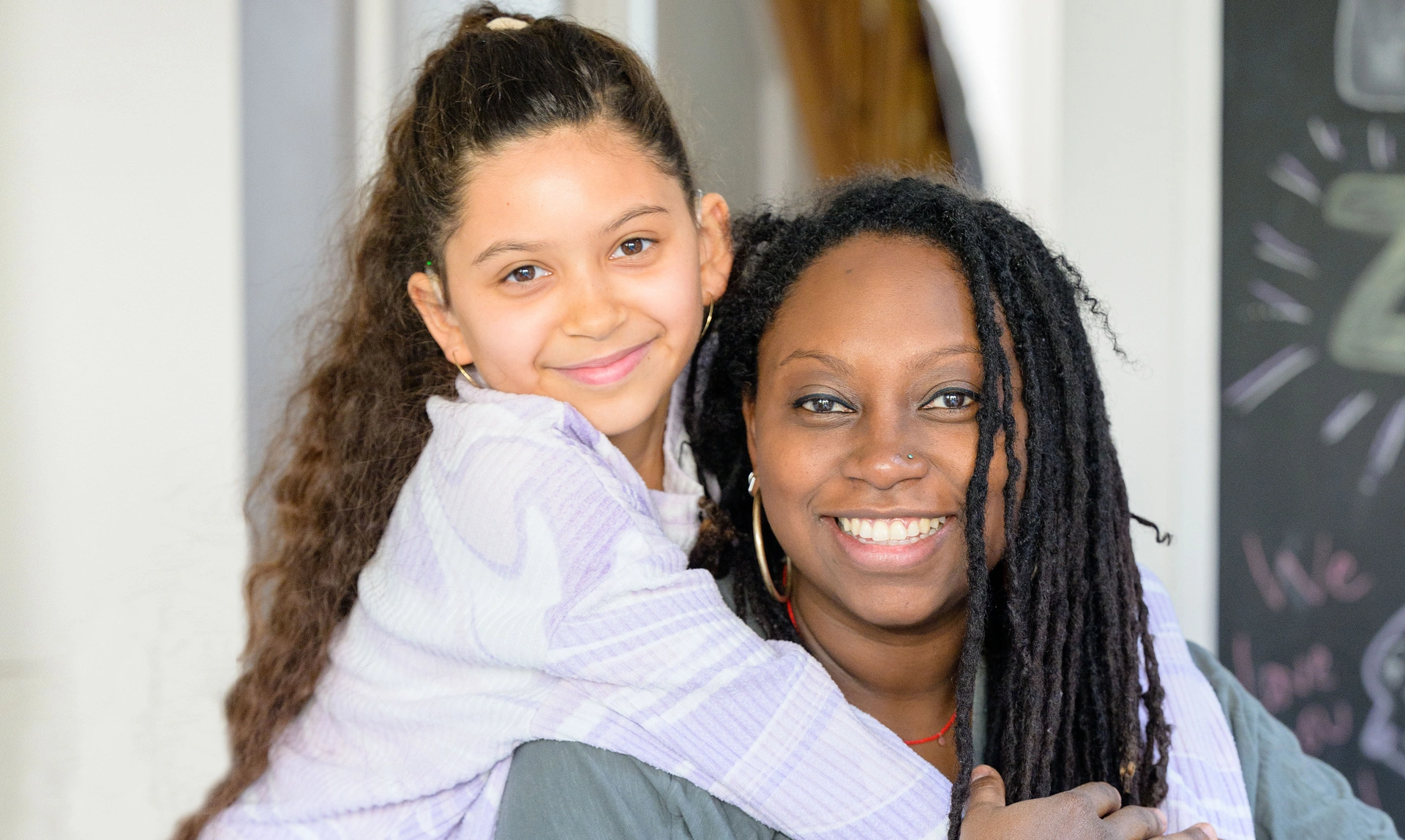 Close up of a mum and her daughter hugging and smiling at the camera