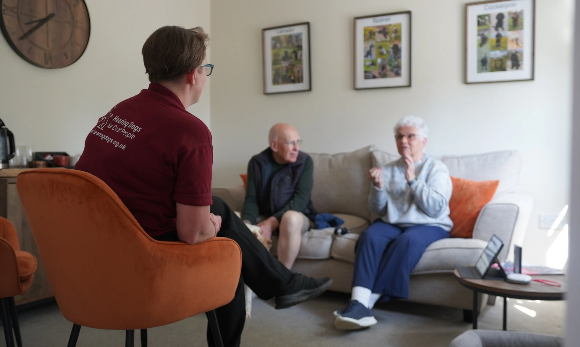 A man and woman in conversation seen from over the shoulder of a woman in hearing dogs staff uniform