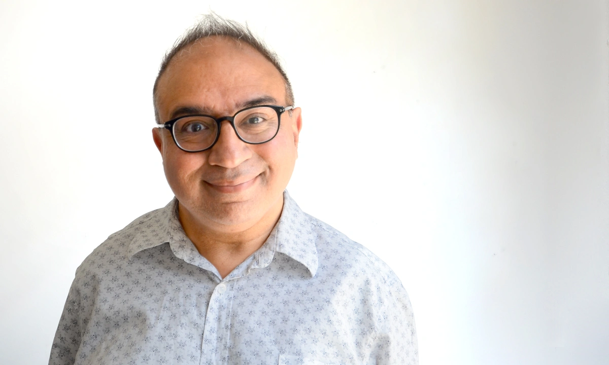 A photo of Harry Hayer, a smiling man with white button down shirt and black spectacles
