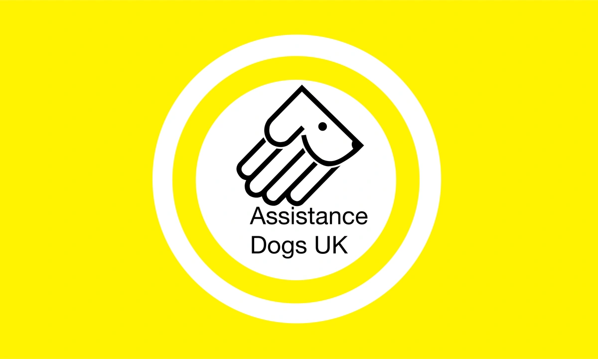 Assistance Dogs logo which is a handle and dog face combined on a yellow background
