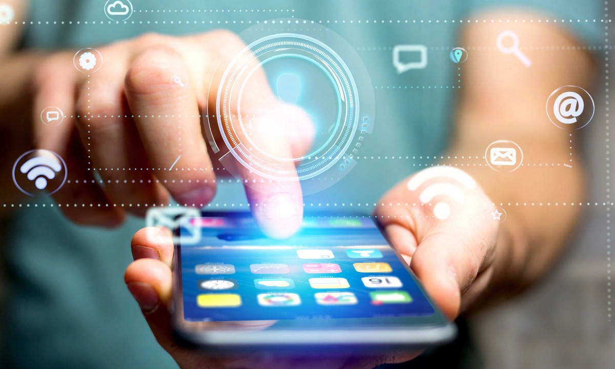 Close up on a hand holding a mobile phone with icons floating in the air around it