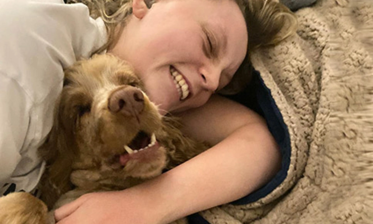 Ameila and hearing dog scamp cuddling