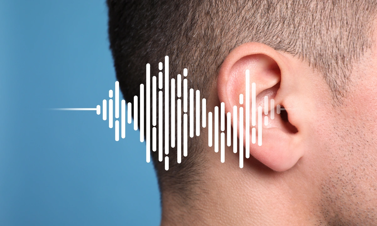 Close up, side view of a person’s ear with white broken soundwaves going into the ear