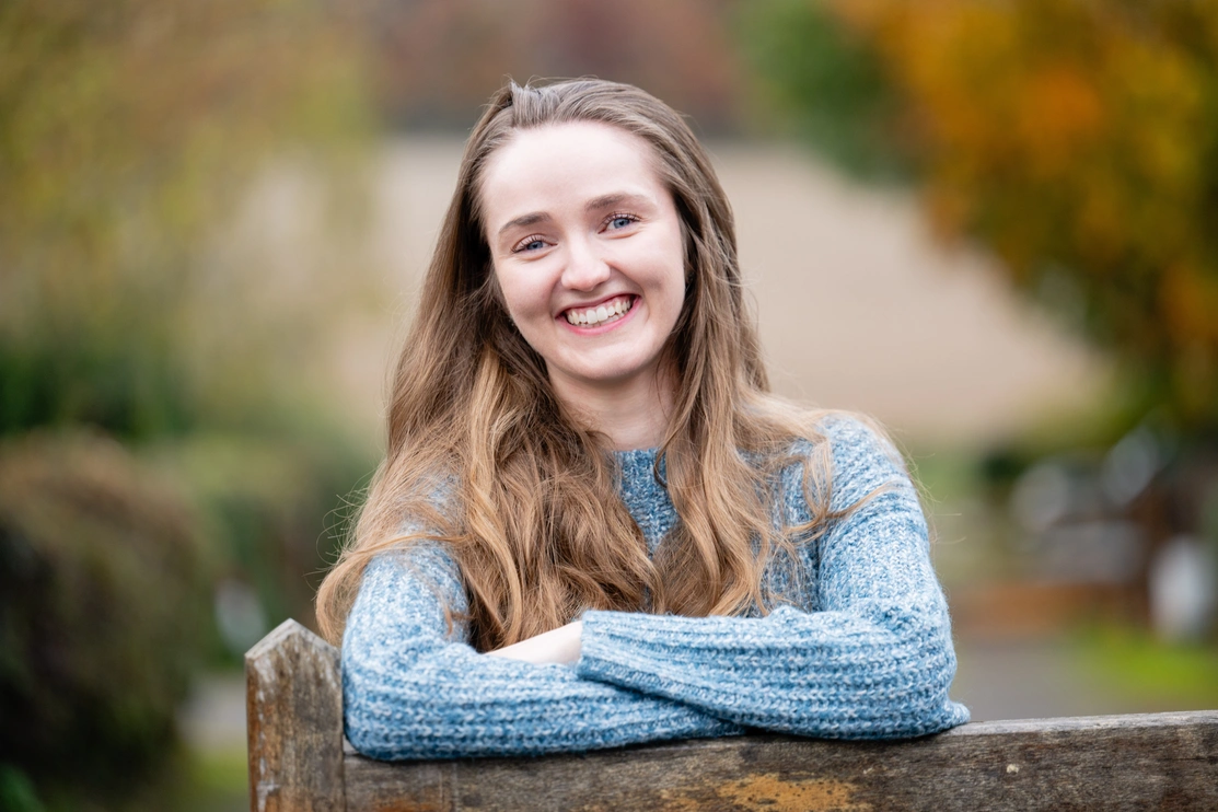 Mid shot of a woman smiling leaning on a wooden gate