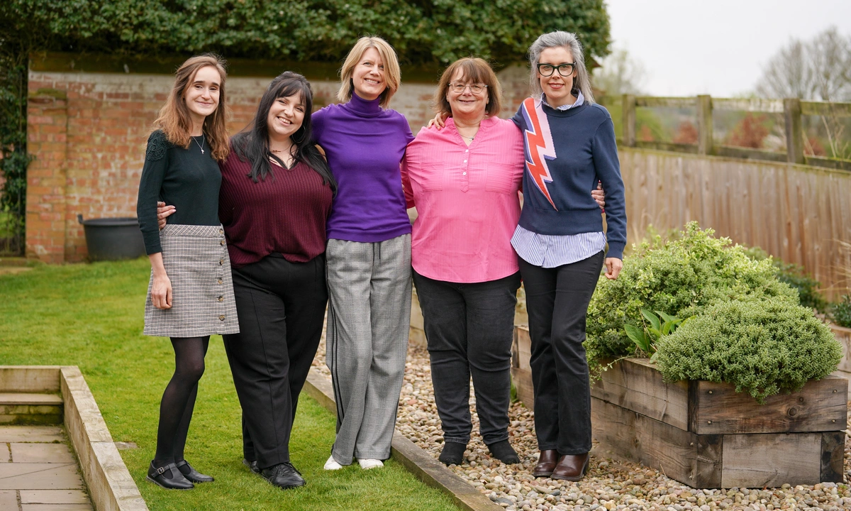 A group of five women standing outside smiling