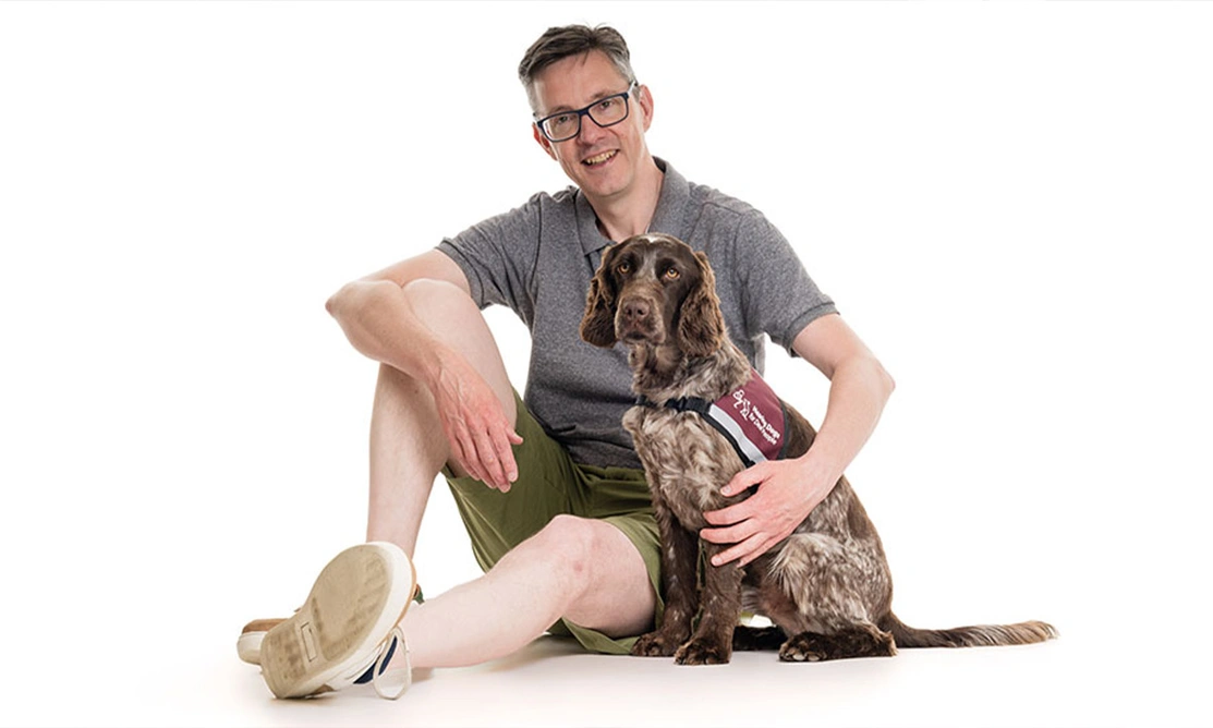 Man sitting on floor with arm around chocolate roan spaniel