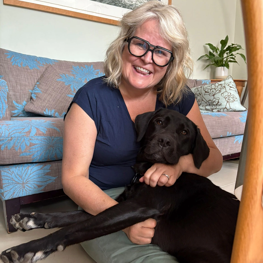 Black Labrador cuddling up to woman sitting on floor