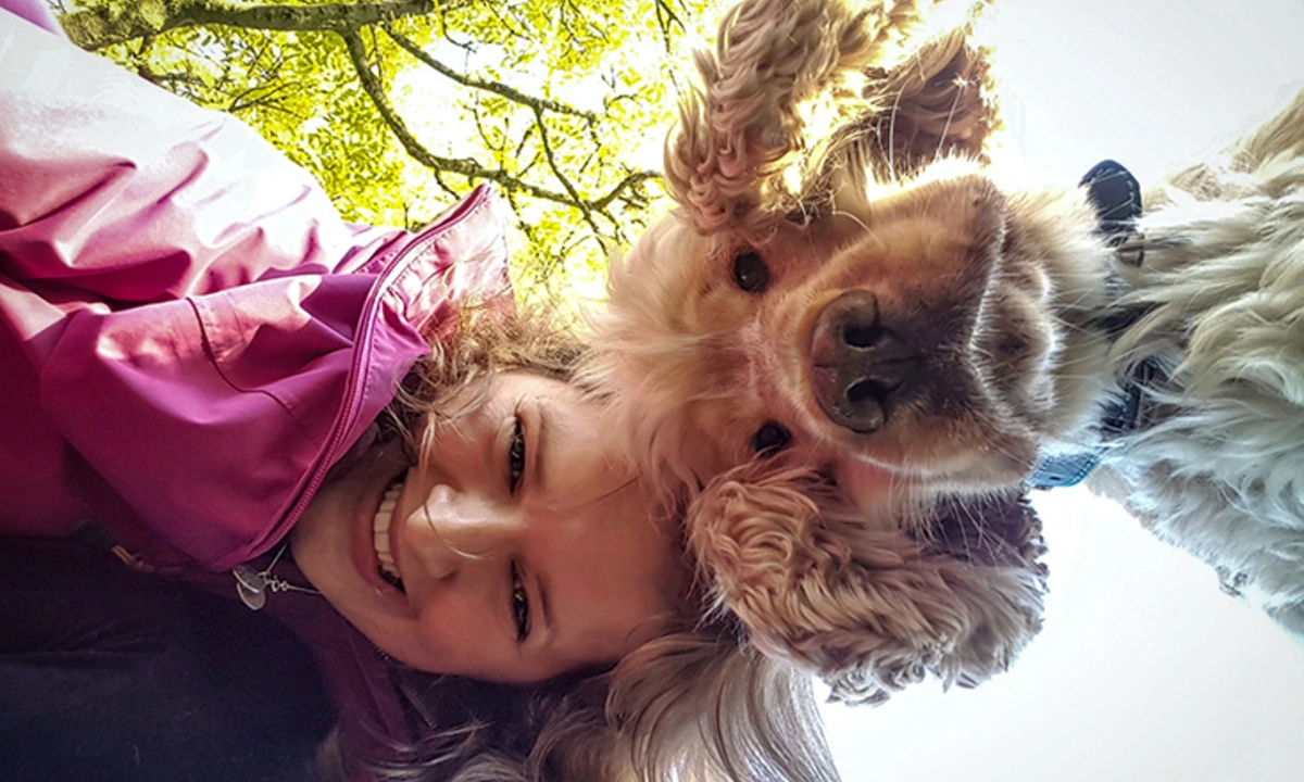 A woman and dog are pictured from looking down on the camera. A tree can be seen in the background also from below.