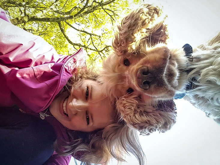 A woman and dog are pictured from looking down on the camera. A tree can be seen in the background also from below.