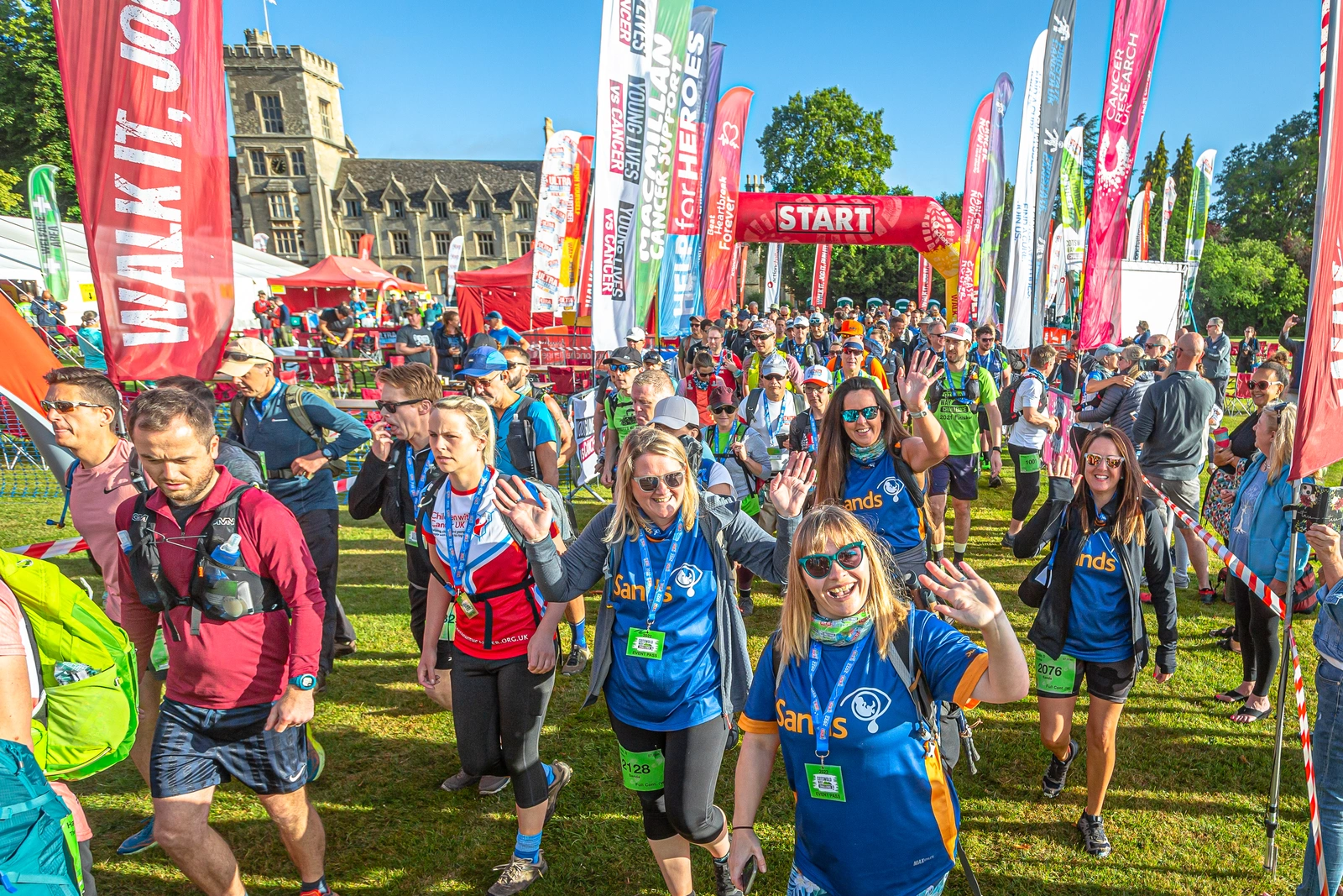 Dozens of runners at the start of a race. A stately home can be seen in the background.