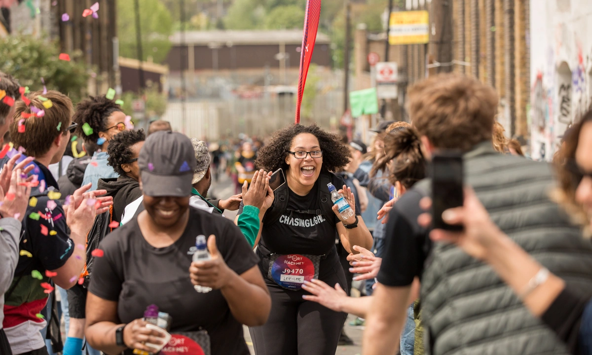 Runners take part in the Hackney Half Marathon as spectators line the route, cheering and offering high-fives while confetti falls around the course.